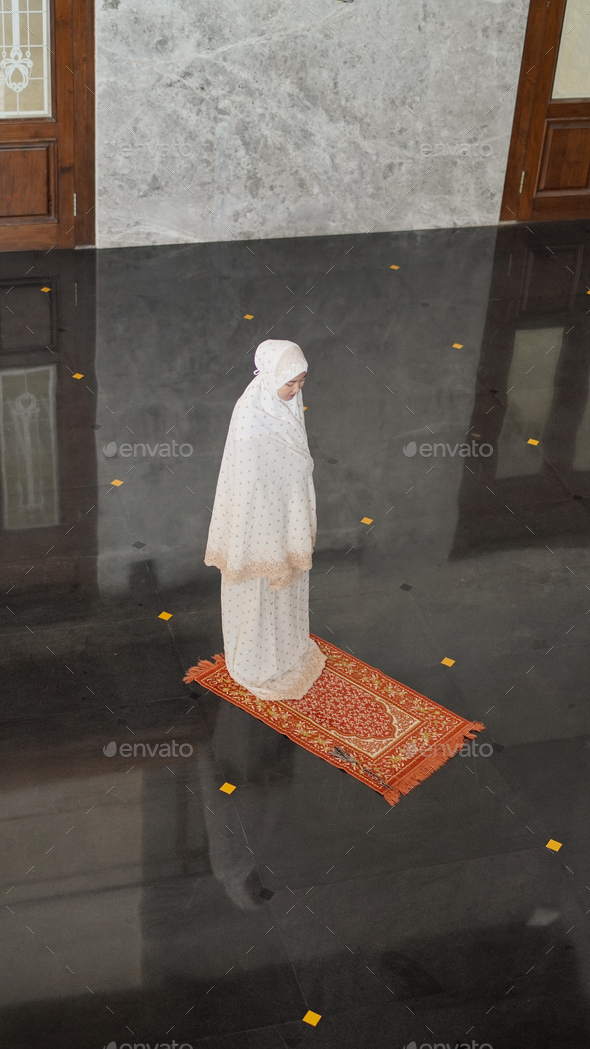 Asian Muslim woman praying alone without imam in mosque Stock Photo by
